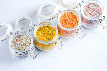 Four jars with different flavoured mixes of salt and spices. Himalayan and sea salt mixed with various peppers and herbs.