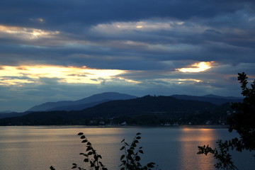 Lake surrounded with mountains. Clouds and sunset.
