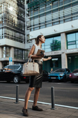 Naklejka premium student with bag and pc tablet in the background of the business center catches a taxi