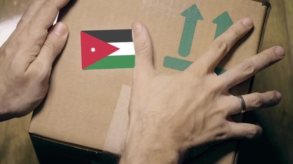 Warehouse worker places sticker with flag of Jordan on the box. Jordanian import or export related clip - Powered by Adobe
