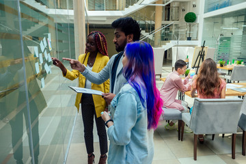 multiracial group standing near wall and put sticky sticker on glass