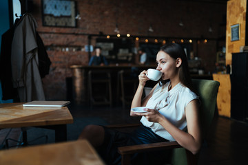 girl drinks coffee in a cafe sitting in a chair