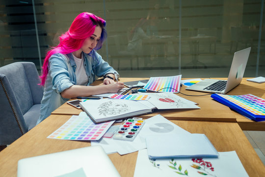 beautiful illustrator woman with pink and blue multi-colored hair draw image on touchscreen in her office studio