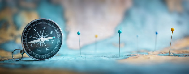 Magnetic compass  and location marking with a pin on routes on world map. Adventure, discovery, navigation, communication, logistics, geography, transport and travel theme concept background.. - obrazy, fototapety, plakaty