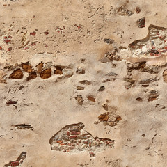 Seamless texture of the old wall with partially flaked plaster and protruding stones and bricks. Pisa. Italy.