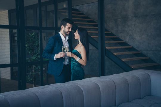 Profile photo of two classy stylish trendy people couple wealthy guy and lady standing close looking eyes drinking sparkling wine romance date wear fancy formalwear suit loft industrial indoors