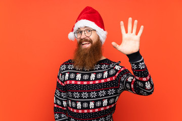 Christmas man with long beard over isolated red background saluting with hand with happy expression