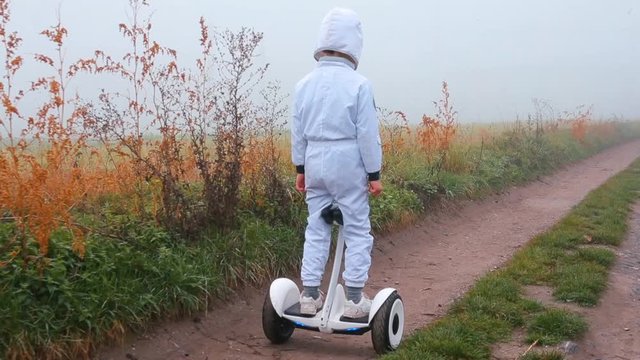 The astronaut on a gyroscooter rides along the road in the fog.