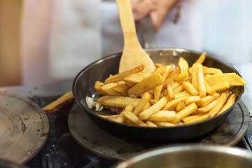 Chef is cooking french fries in the kitchen, cook preparing delicious French fries