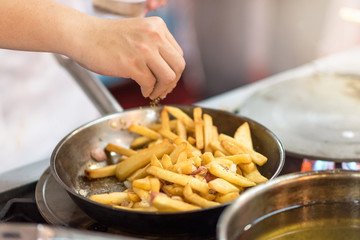Chef is cooking french fries in the kitchen, cook preparing delicious French fries