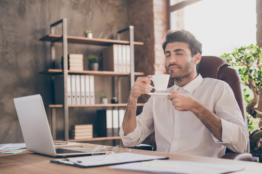 Profile side photo of calm middle eastern businessman have break hold mug smell hot beverage enjoy with closing eyes sit chair table in loft office