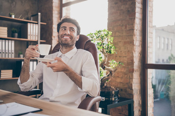 Portrait of calm cheerful middle eastern marketer hold cup mug with hot beverage espresso dream about future weekends feel content sit chair desktop in loft office