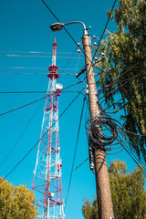 Lamp pole  lot of electric wires hangs from above the TV tower at blue sky background, Yoshkar-Ola...