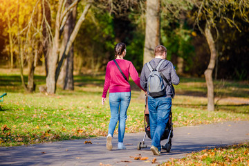 Obraz premium A married couple rolls a baby stroller in a city Park 