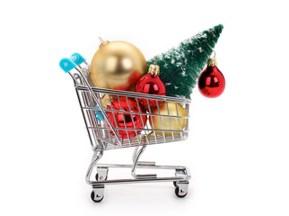 Christmas shopping concept. Miniature shopping cart with christmas balls and tree on white background.