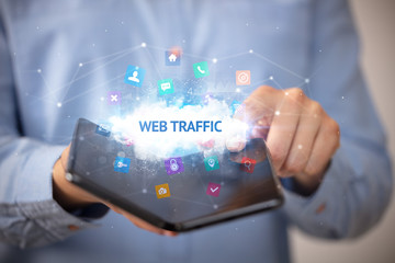 Businessman holding a foldable smartphone with WEB TRAFFIC inscription, technology concept