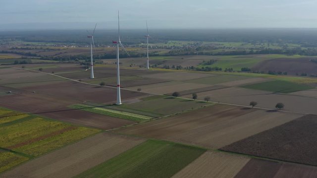 Aerial view of wind turbines beside vineyards in Germany. On a sunny day in Autumn, fall. Pan to the left around the turbines.