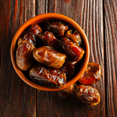 Clay brown bowl with dried dates on a wooden table. Healthy sweets, healthy nutrition. Traditional dessert in ramadan.