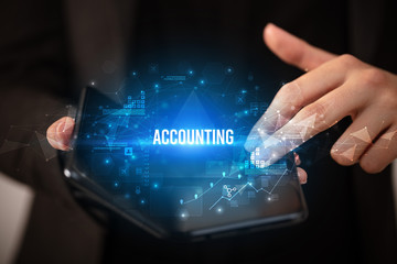 Businessman holding a foldable smartphone with ACCOUNTING inscription, business concept
