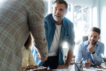 Welcome to our team! Business men in smart casual wear shaking hands while working in the creative office.