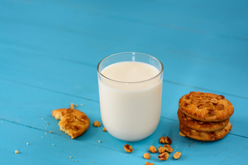 A glass of milk, homemade cakes (oatmeal cookies with nuts)  on a blue wooden background.
