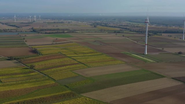 Aerial view of wind turbines beside vineyards in Germany. On a sunny day in Autumn, fall. Pan to the right beside the turbines.