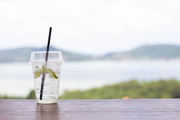 1 glass of water laid on a wooden background, the background is mountains and the sea.