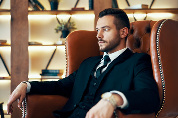 Confident young man relax in armchair in luxury interior