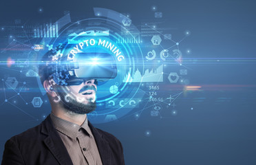 Fototapeta premium Businessman looking through Virtual Reality glasses with CRYPTO MINING inscription, innovative technology concept