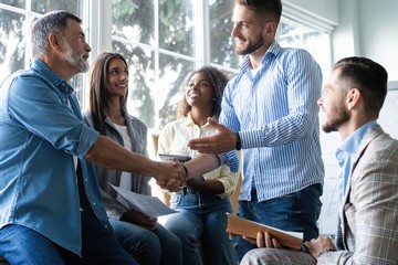 Welcome to our team! Business men in smart casual wear shaking hands while working in the creative office.