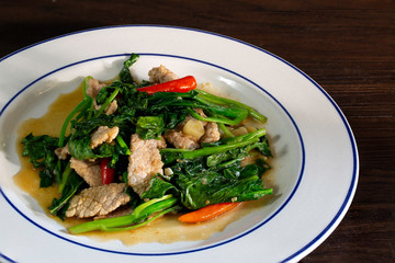 Stir fried kale with pork in white dish, Thai food