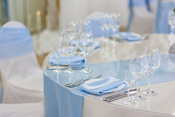 Wine glasses are on the table in the restaurant. White plates with blue tablecloths