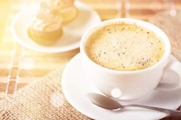 Cup of coffee and scattered coffee beans on wooden background