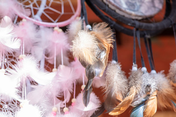 Fototapeta na wymiar A lot of beautiful decorative amulets dream catcher with feathers at the fair