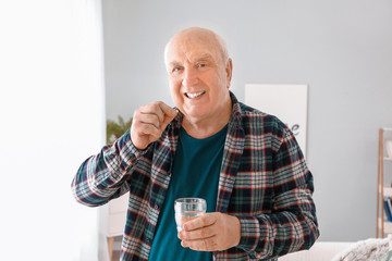 Elderly man taking medicine at home