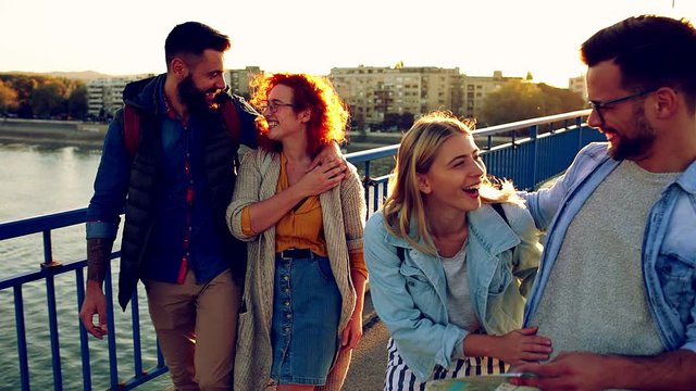 Group of tourists enjoying on vacation, young friends having fun walking on city street during sunset.
