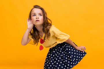 little girl eavesdrops on a conversation, a child holds a palm by the ear against the background of...