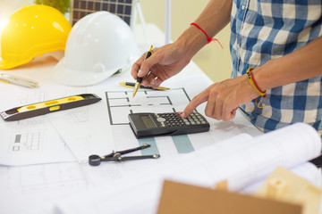 Architect calculating budge Construction project with blueprint  at Construction Site.concept
