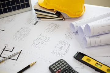 Desk of Architectural working solar panel home project in construction site,With drawing equipment concept.