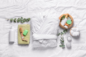 Clean bathrobe with spa supplies on white background
