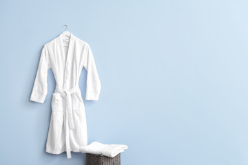 Clean bathrobe hanging on wall in room - obrazy, fototapety, plakaty