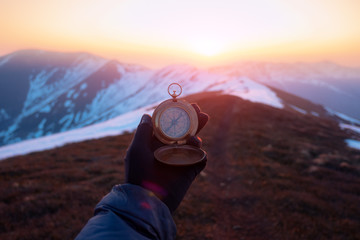 Man with retro compass in high snowy mountains on sunrise time. Travel concept. Landscape photography