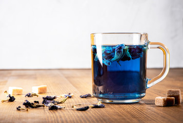 Organic blue Anchan tea in a transparent glass cup on a wooden table. Blue tea Clitoria, Butterfly Pea. 