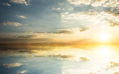 Blue sky with clouds and sun reflection in water