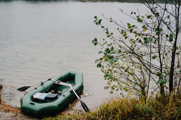 An inflatable boat, with boxes with fishing tackles, is standing on the water, pond, lake, near the shore on the background of tree, nature. Fishing background.