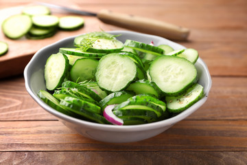 Plate with fresh cucumber salad on wooden background