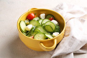 Pot with fresh vegetable salad on light background