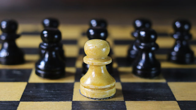 one white chess piece against a background of black pieces.