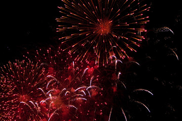 pink, golden and white sparks of fireworks exploding in the sky and smoke from the charges