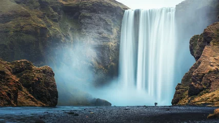 Fotobehang Donkergrijs Paar toeristen dichtbij beroemde Skogafoss-waterval, IJsland